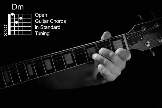 Open Guitar Chords in Standard Tuning guitar tutorial series. Closeup of hand playing Dm chord on guitar, on black background. Black and white photo.