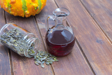 Natural organic pumpkin seed oil in a glass jar on wooden table. Image with copy space