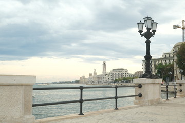 Fototapeta na wymiar Promenade of Bari with the buildings of the Murattiano village. A parapet and a street lamp on the road that runs along the sea.
