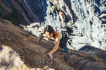 Naklejka na ściany i meble Woman climbs a rock.