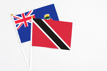Trinidad And Tobago and Cayman Islands stick flags on white background. High quality fabric, miniature national flag. Peaceful global concept.White floor for copy space.