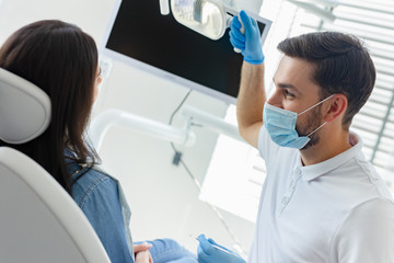 portrait of male dentist adjusting lamp in the hospital