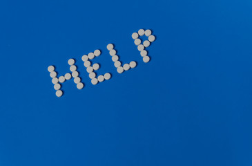 Syringe and HELP from pills on a blue background. Addiction concept and HIV prevention