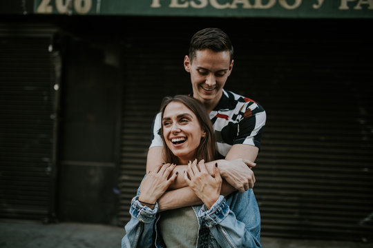 Young laughing couple embracing in urban area