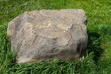 The boulder is lying on the grass