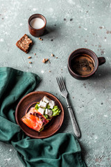Tasty breakfast. Bread toast with cream cheese, red fish and green lettuce on the table. Flat barking. Healthy food.