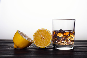Whiskey in a glass with ice and lemon on a wooden background