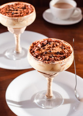 italian dessert tiramisu in an elegant cocktail glass, the concept of sweet life, luxury, delicious food