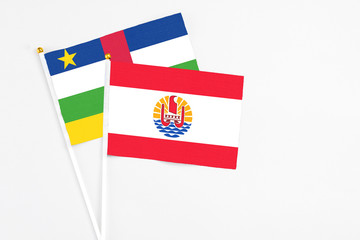 French Polynesia and Central African Republic stick flags on white background. High quality fabric, miniature national flag. Peaceful global concept.White floor for copy space.
