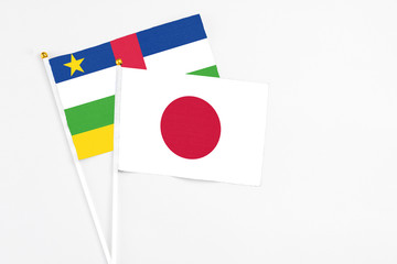 Japan and Central African Republic stick flags on white background. High quality fabric, miniature national flag. Peaceful global concept.White floor for copy space.