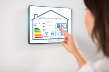 automation, internet of things and technology concept - woman using tablet pc computer with energy saving options at smart home
