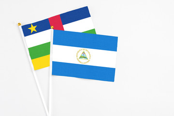 Nicaragua and Central African Republic stick flags on white background. High quality fabric, miniature national flag. Peaceful global concept.White floor for copy space.