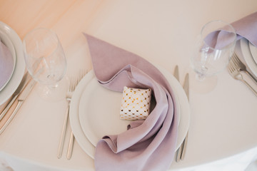 Coziness and style. Modern event design. Table setting at wedding reception. Floral compositions with beautiful flowers and greenery, candles, laying and plates on decorated table.