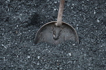  A metal scoop is inserted into the mass of a coal bayonet.