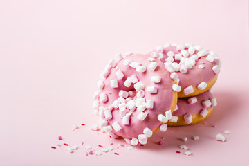 Pink glazed donuts with marshmallows on pink background