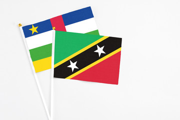 Saint Kitts And Nevis and Central African Republic stick flags on white background. High quality fabric, miniature national flag. Peaceful global concept.White floor for copy space.