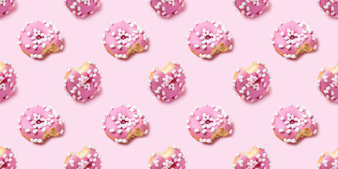 Seamless texture with Bitten icing donut on pink background, isometric view