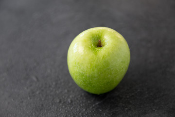fruits, diet, eco food and objects concept - ripe green apple on slate stone background