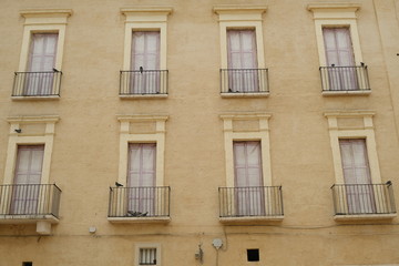 Fototapeta na wymiar Facade of a Mediterranean palace with windows and balconies. Beige color plaster.