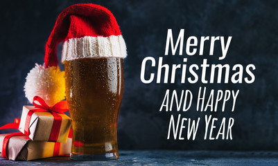 Glass beer mug in a Christmas Santa hat on a dark background . Merry Christmas and happy new year
