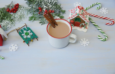 christmas composition with gingerbread cookies, mug of cocoa, caramel canes gingerbread house and decorations on blue background with copy space for text. Top view
