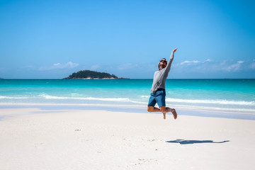 Guy jumping in on the Whitehaven Beach in front of Esk Island, Whitsundays, Queensland, Australia