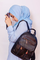 Modern Muslim student girl in hijab. Young middle-eastern college student with backpack holding books and notepads. Isolated on white background. Portrait of young Arabian woman student