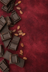 dark bitter chocolate with organic cocoa beans on a red background with copy space for text. Confectionery ingredient. Background, pattern, postcard, menu. Flat lay. Top view. Vertical photo.