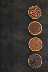 organic cacao beans, cocoa powder, ground and chocolate on a black background with copy space for text. Flat lay, top view. Ingredient. Vegan food. Background, pattern, card, menu. Vertical photo.