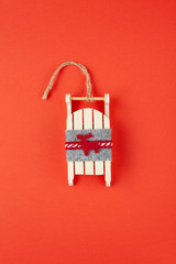Christmas decoration, tree toy, wooden sled with deer on red background, for social media. Festive, New Year concept. Vertical, flat lay. Minimal style. Top view