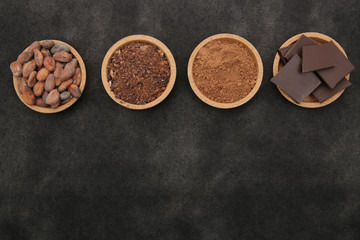 organic cacao beans, cocoa powder, ground and chocolate on a black background with copy space for...