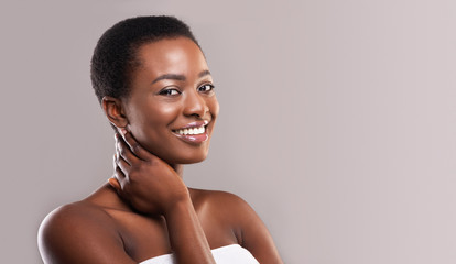 Smiling beautiful black girl touching her soft skin on neck