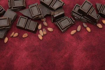 dark bitter chocolate with organic cocoa beans on a red background with copy space for text. Confectionery ingredient. Background, pattern, postcard, menu. Flat lay. Top view.