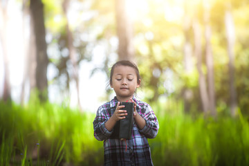 little girl standing and praying to God with Bible in nature. christian concept.