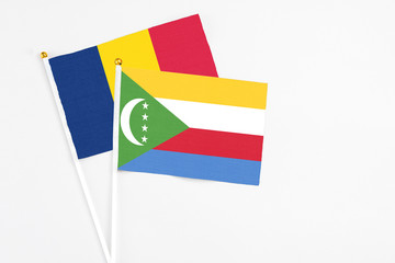 Comoros and Chad stick flags on white background. High quality fabric, miniature national flag. Peaceful global concept.White floor for copy space.