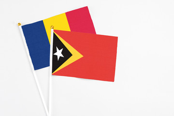 East Timor and Chad stick flags on white background. High quality fabric, miniature national flag. Peaceful global concept.White floor for copy space.