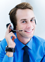 Portrait of happy smiling young support phone attractive male operator in headset, at workplace....