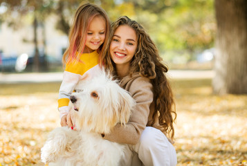 Beautiful, happy young mother with little girl and dog outdoor.