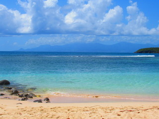 Une plage de sable blanc et la mer turquoise avec une ile lointaine