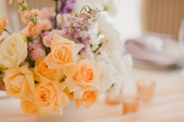 Coziness and style. Modern event design. Table setting at wedding reception. Floral compositions with beautiful flowers and greenery, candles, laying and plates on decorated table.