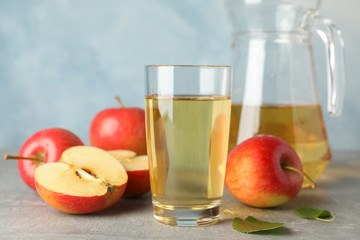 Red apples and glasses with juice on grey background, space for text