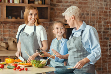 Little girl happy to help mom and granny with dinner