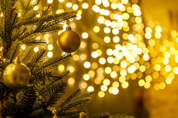 Christmas and New Year interior - blur background: fireplace, lamps, green Christmas tree, brown leather sofa, gifts, candles, moose rocking chair. Lots of lights glowing in the dark.