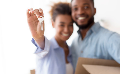 Happy Afro Couple Showing Keys Embracing Standing Indoor, Selective Focus