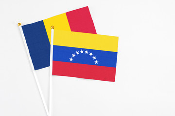 Venezuela and Chad stick flags on white background. High quality fabric, miniature national flag. Peaceful global concept.White floor for copy space.