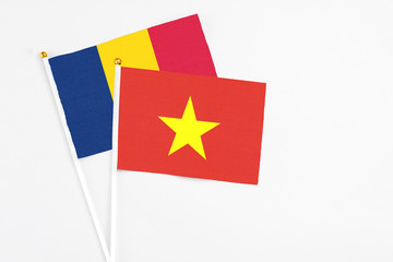 Vietnam and Chad stick flags on white background. High quality fabric, miniature national flag. Peaceful global concept.White floor for copy space.