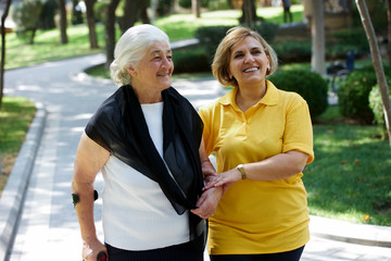 Professional caregiver taking care of senior woman, outdoors.