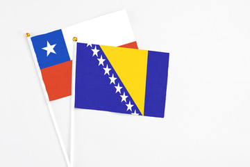 Bosnia Herzegovina and Chile stick flags on white background. High quality fabric, miniature national flag. Peaceful global concept.White floor for copy space.
