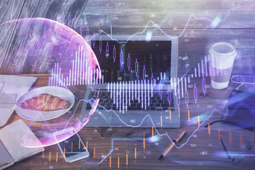 Double exposure of graph and financial info and work space with computer background. Concept of international online trading.