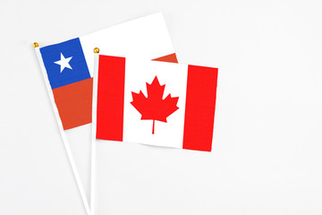 Canada and Chile stick flags on white background. High quality fabric, miniature national flag. Peaceful global concept.White floor for copy space.